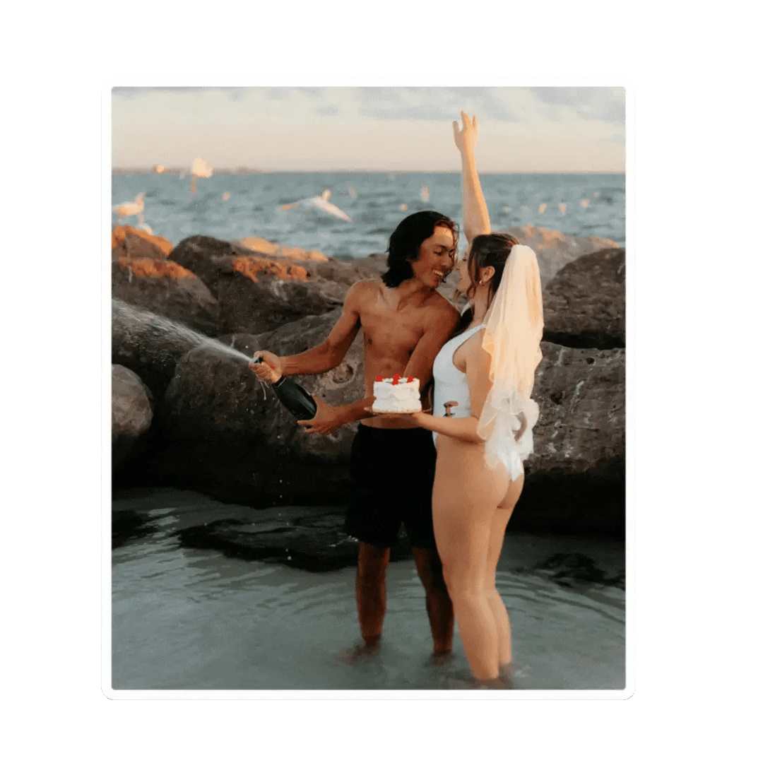 just married couple popping champagne on the beach