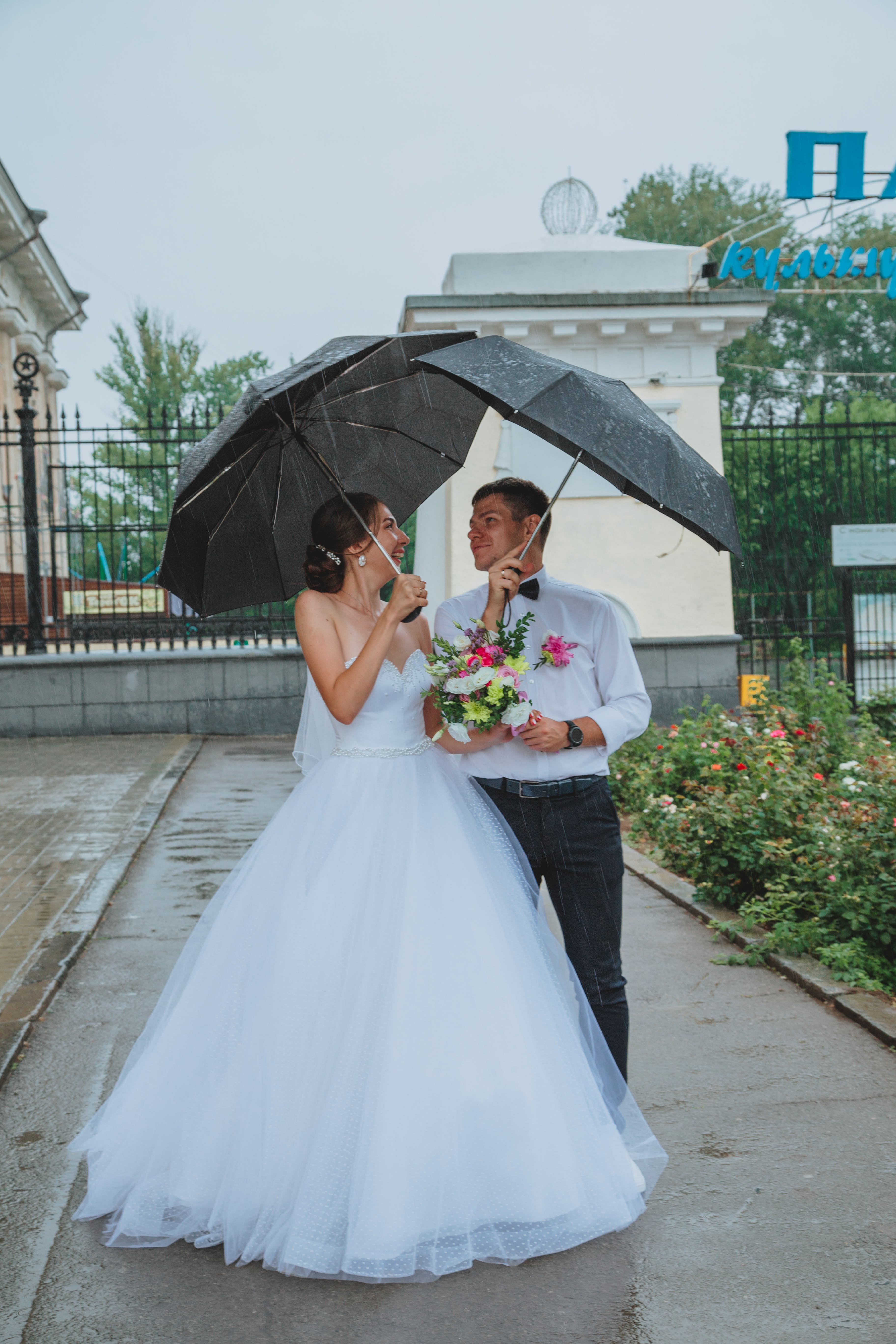 a wedding couple under black umbrellas in the rain